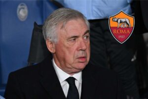 Carlo Ancelotti osserva alla sua destra lo stemma della Roma